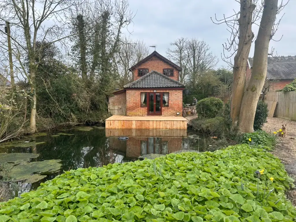 Brick garden house overlooking pond with wooden deck