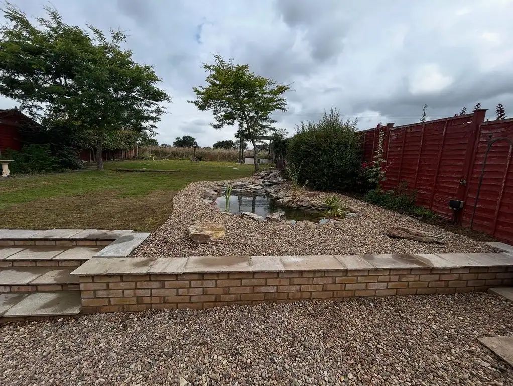 Landscaped garden with pond and red fencing