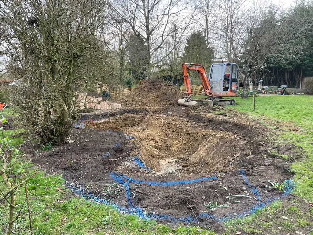 Excavator digging large hole in garden