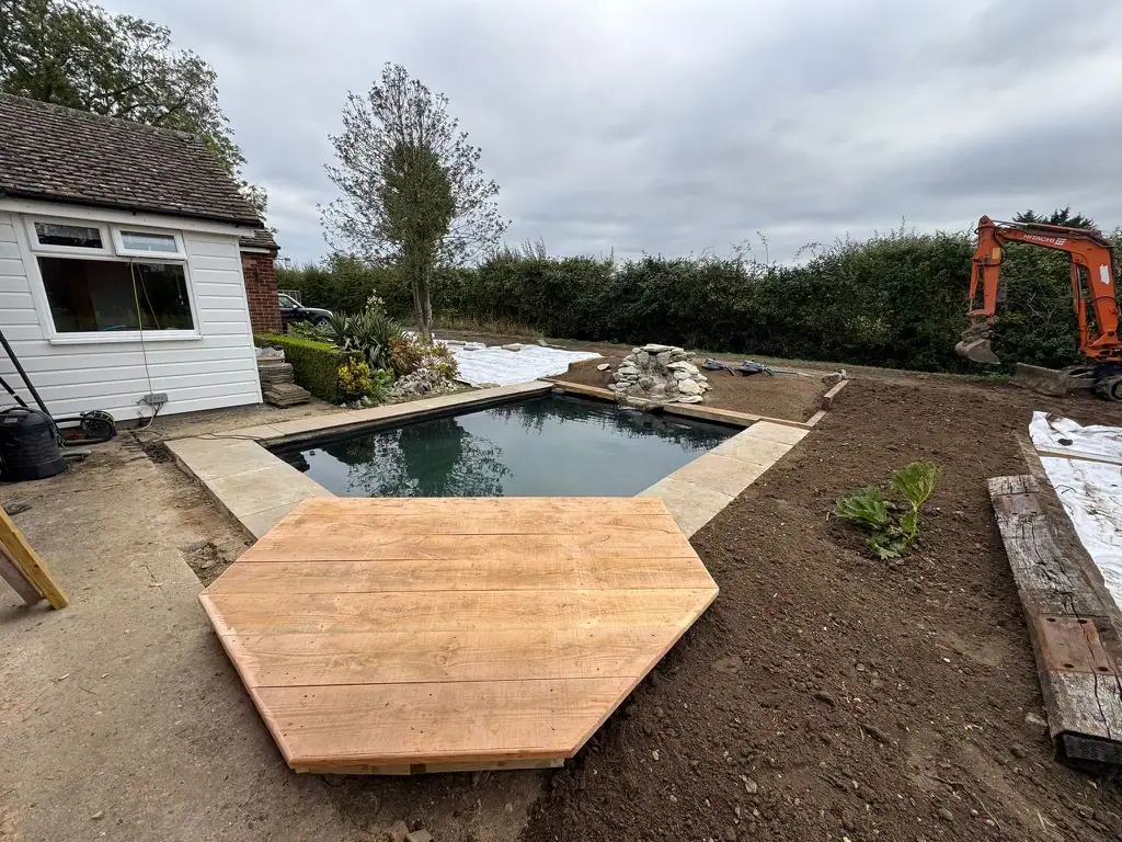 Garden pond with new wooden deck and excavator