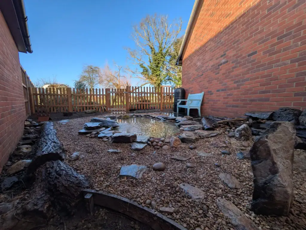 Small gravel garden with pond and wooden fence