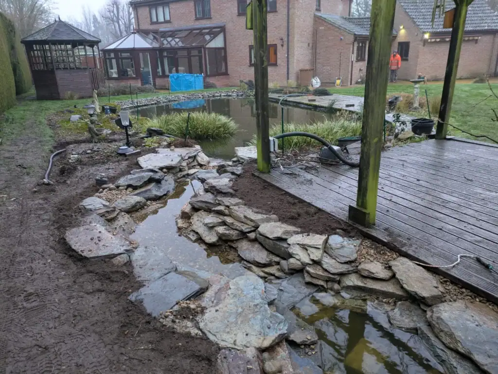 Garden pond and rock stream beside wooden decking